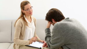 stock-footage-young-man-sitting-on-sofa-talking-to-his-therapist-at-therapy-session